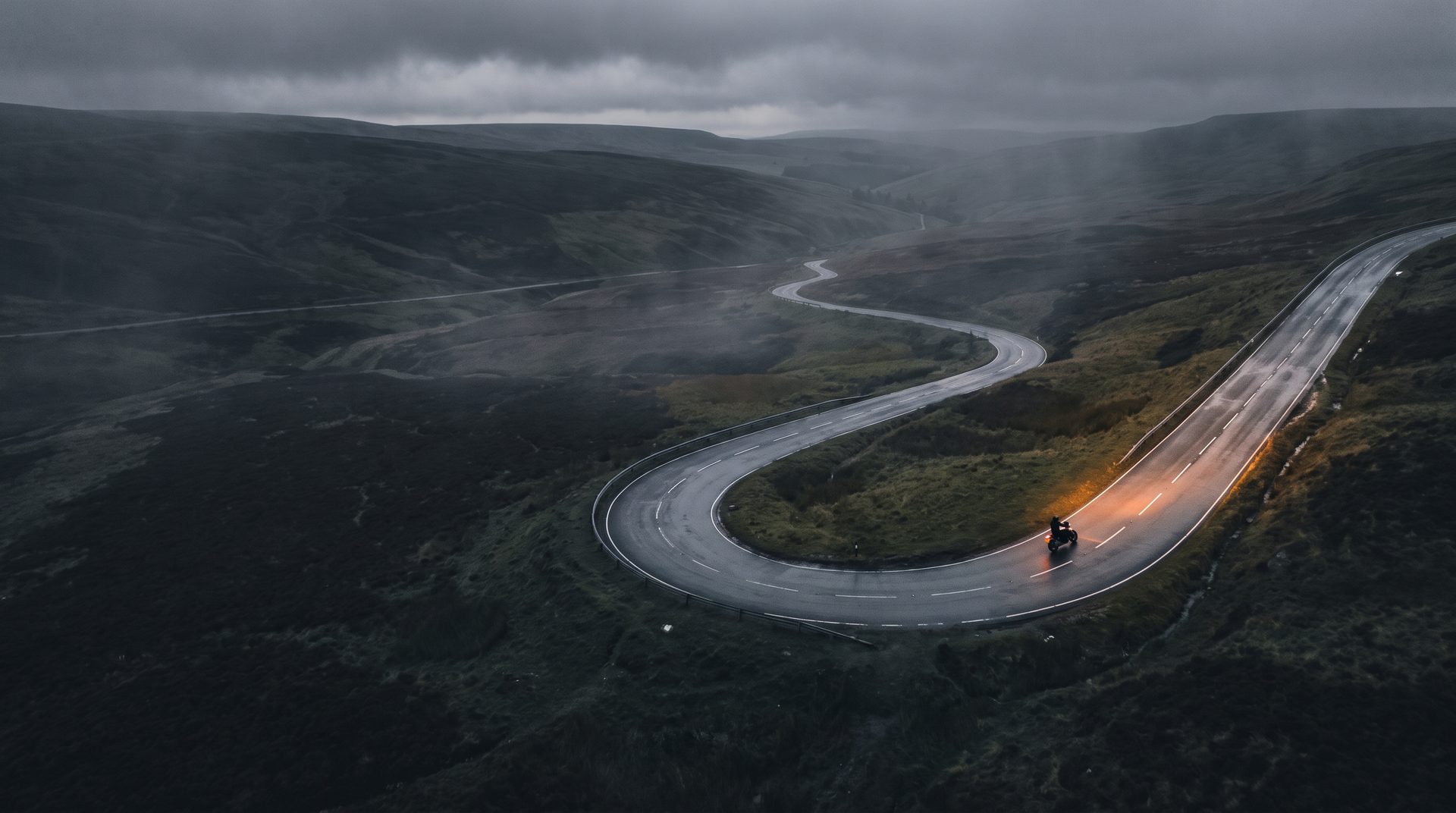 A motorcycle leaning through a bend on an empty British moorland road.